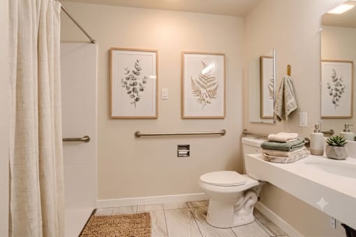 A bathroom with a toilet, sink, and two wall art pieces.