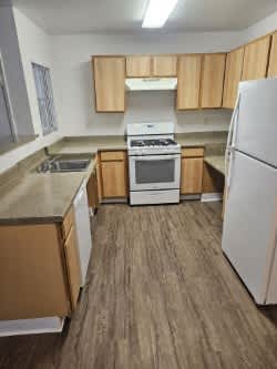 A kitchen with a white refrigerator, brown cabinets, and a white stove top oven.