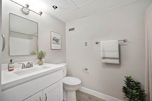 A white bathroom with a toilet, sink, and mirror.