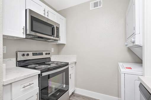 A kitchen with white cabinets and appliances.