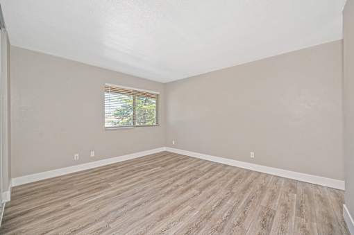 Empty room with wooden flooring and a window.