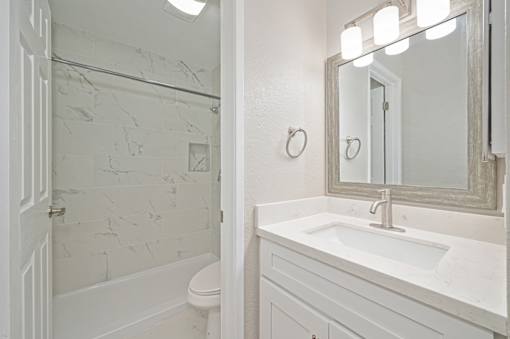 A white bathroom with a marble tile shower.