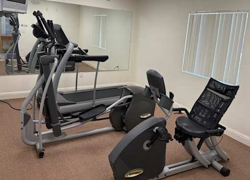 A gym with a treadmill, elliptical trainer and a stationary bike.