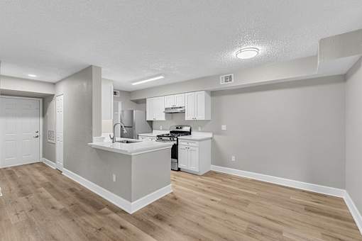 A kitchen with white cabinets and a wooden floor.