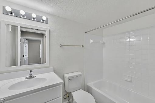 A white bathroom with a toilet, sink, and bathtub.