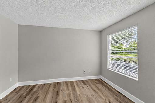 A room with wooden floors and a window with blinds.