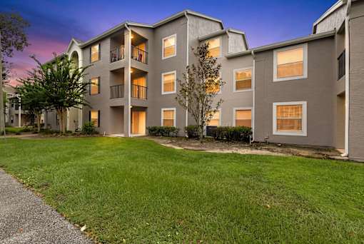 A modern apartment building with a well-maintained lawn in front.