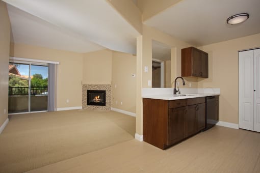 an empty living room with a fireplace and a kitchen