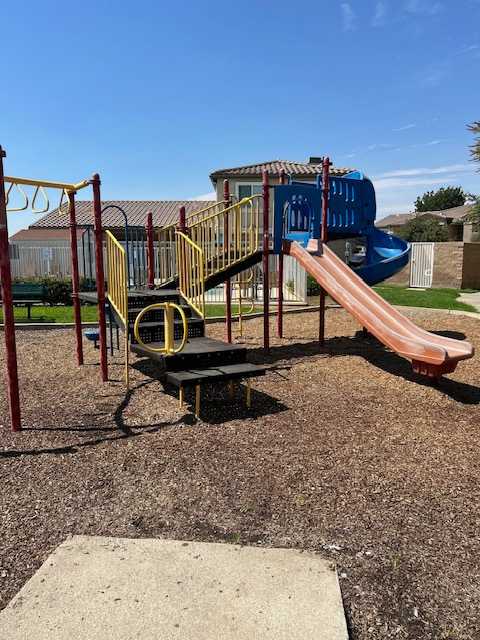 A playground with a blue slide and a yellow and black play structure.