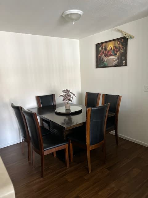 A dining table with four chairs and a vase with flowers on it.