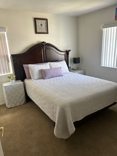 A bed with a white comforter and a wooden headboard.