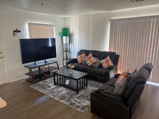 A living room with a black couch and a flat screen TV.