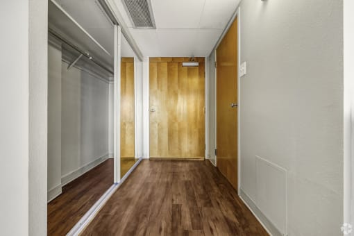a hallway with wood floors and white walls and a door