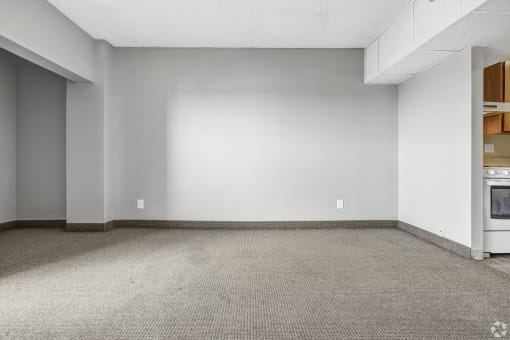 the living room of an empty house with a white wall and a stove