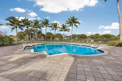 A swimming pool surrounded by palm trees and a tiled floor.