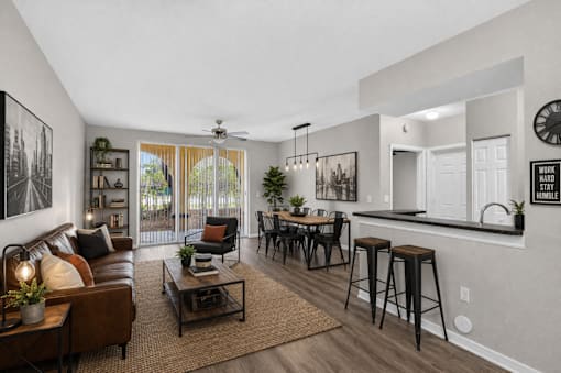 A living room with a brown leather couch, a coffee table, and a bar area with stools.
