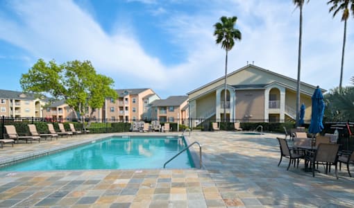 Swimming pool with patio seating and palm trees at The Ivy at Gatehouse Apartments, Orlando, FL