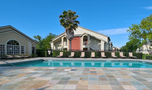 Resort style swimming pool with lounge chairs at The Ivy at Gatehouse Apartments, Orlando, Florida