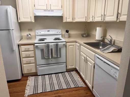 A kitchen with a white oven and white cabinets.