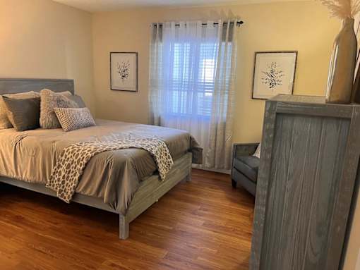 A bedroom with a bed, a nightstand, and a wooden dresser.