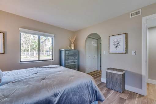 A bedroom with a bed, dresser, and window.