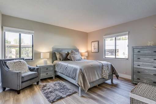 A bedroom with a bed, chair, and nightstand.