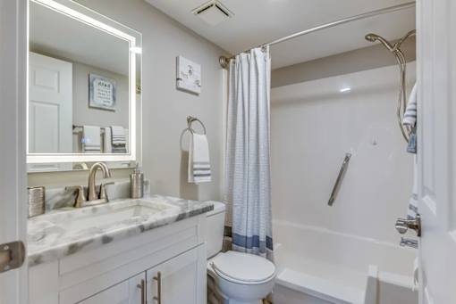 A white bathroom with a marble countertop and a white toilet.