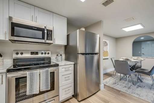 A modern kitchen with stainless steel appliances and a dining area.