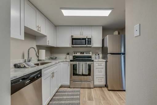 A kitchen with white cabinets and a stainless steel refrigerator.