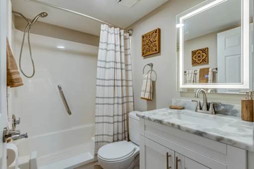 A white bathroom with a marble countertop and a toilet.
