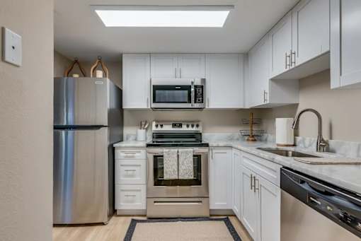 A modern kitchen with white cabinets and stainless steel appliances.