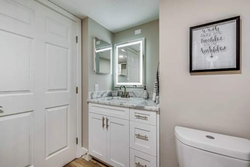 A bathroom with a toilet, sink, and a mirror.