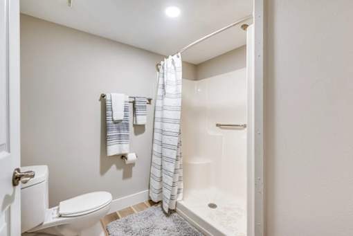 A white toilet sits next to a white bathtub in a small bathroom.