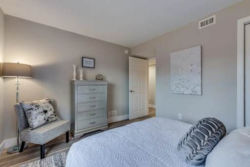 A bedroom with a bed, chair, and dresser.