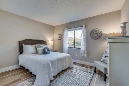 A bedroom with a bed, a bench, and a window.