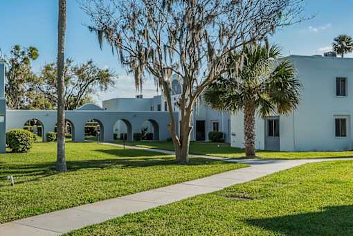 A white building with a tree in front of it.