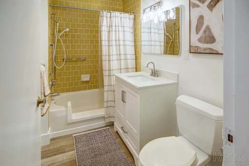 A bathroom with a yellow tiled shower area and a white toilet.