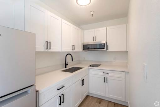 A kitchen with white cabinets and a white fridge.