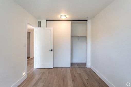 A white door is open to a room with a wooden floor.