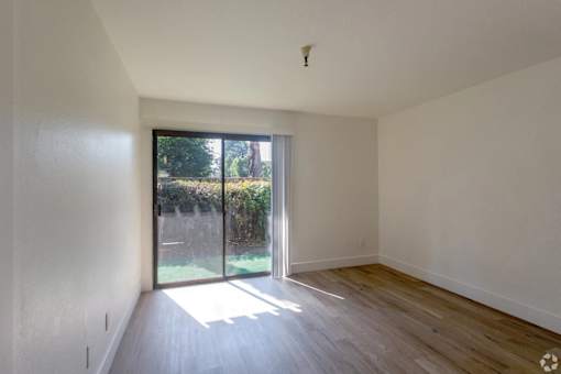 A room with a sliding glass door leading to a garden.