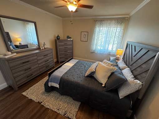 A bedroom with a bed, dresser, and mirror.