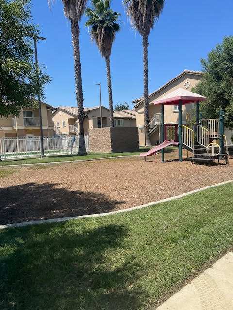 A playground with a slide and a swing set in a residential area.