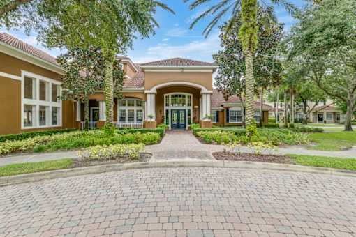 A brick pathway leads to a building entrance surrounded by greenery.