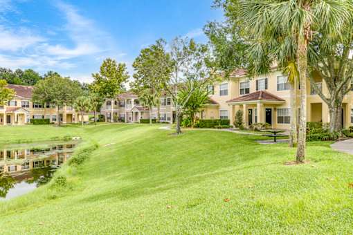 A row of houses with a pond in front of them.