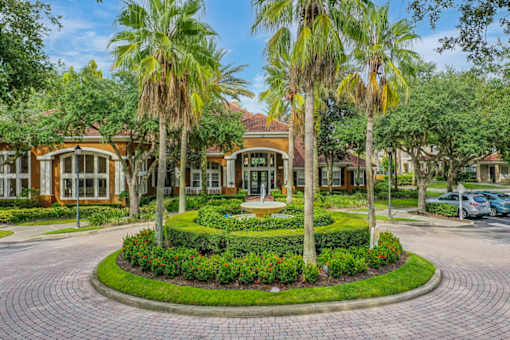 A building with a landscaped front yard and palm trees.