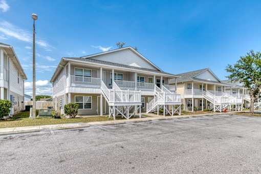 A row of houses with white balconies and a clear blue sky.