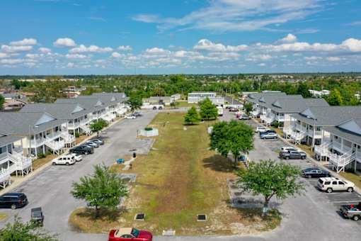A parking lot with cars and a grassy area in the middle.
