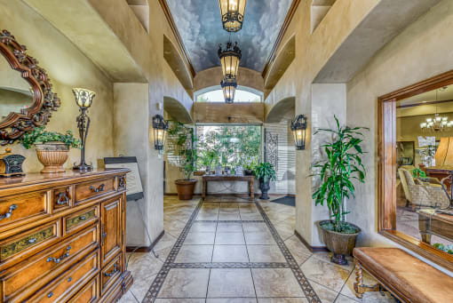 the entryway of a house with a tiled floor and a tree in the
