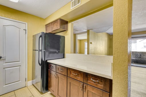 a kitchen with a refrigerator and wooden cabinets