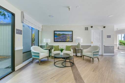 A modern living room with a glass door and a painting on the wall.